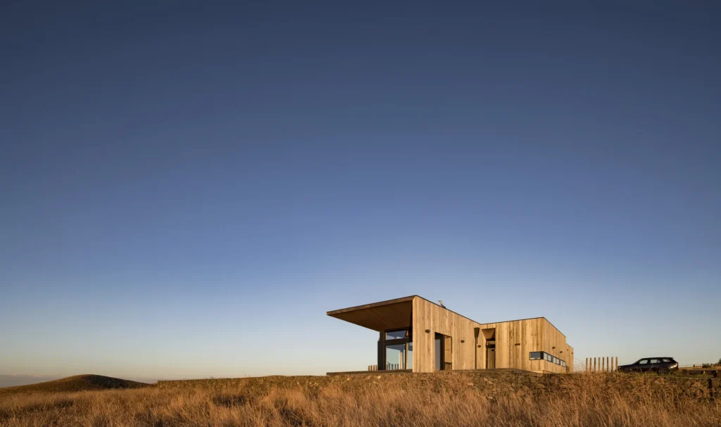 Casa contemporânea de linhas horizontais numa encosta seca, ao entardecer.