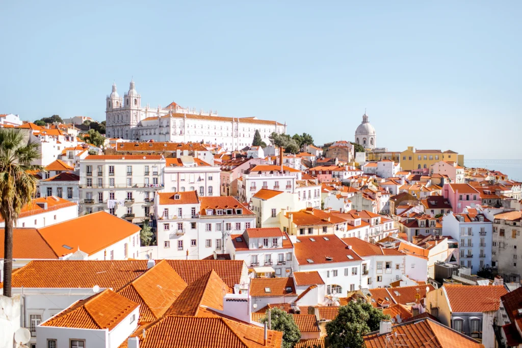 Telhados de Lisboa com uma colina e igreja ao fundo.